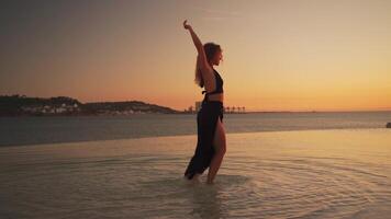 femmina ballerino danza nel acqua a tramonto luce. video