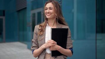 a woman is standing in front of a building holding a book video