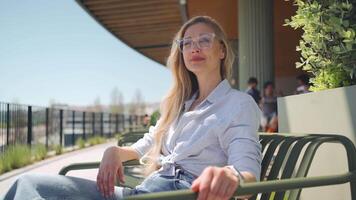 a woman in glasses sitting on a bench video