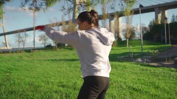 mulher sombra boxe com dela mãos embrulhado dentro vermelho boxe fitas dentro parque com soco caixa. video