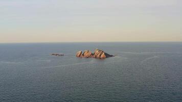 An abandoned lighthouse on top of a rocky island at sunrise video