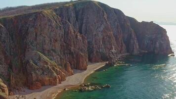 rochoso de praia em a mar costa com Claro água e lindo vertical pedras video