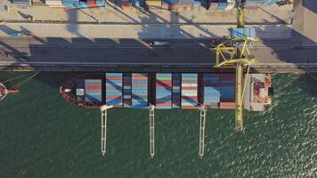 Aerial top down. containers being unloaded by a crane from a container ship video