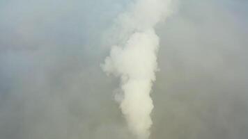 Smoke from a power station chimney rising from a low, creeping fog. Drone view video