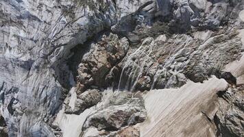 Glacier covered with stone rocks, deep cracks and small waterfalls video