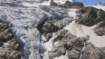 glacier couvert avec pierre rochers, Profond des fissures et petit cascades video