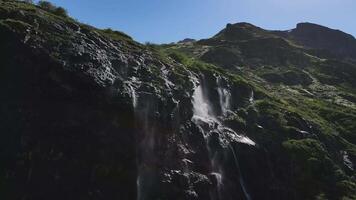 Wasser fließt Nieder das Steigung von ein Berg Tropfen Spritzen von ein enorm Felsen video