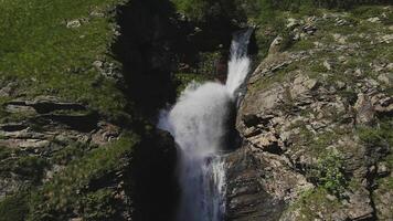 antenne visie van een krachtig stroom van een berg waterval Aan een zonnig zomer dag video