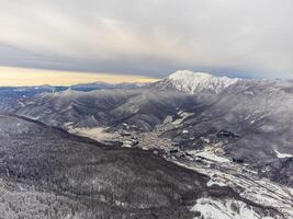 ver de el invierno puesta de sol y cubierto de nieve montañas en Sochi foto