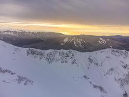 ver de el invierno puesta de sol y cubierto de nieve montañas en Sochi foto