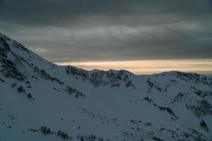 ver de el invierno puesta de sol y cubierto de nieve montañas foto