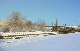 muchos rieles y durmientes viejos se apilan en un almacén ferroviario en invierno. el concepto de renovación de una vía férrea desgastada foto