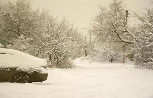 Photo of a car covered in a thick layer of snow. Consequences of heavy snowfall