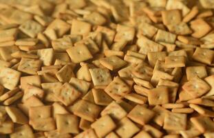 Background texture of small edible squares baked from dough and sprinkled with salt. A lot of salt cracker photo