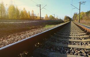 Autumn industrial landscape. Railway receding into the distance among green and yellow autumn trees photo