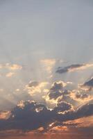 Beautiful sunrise with warm orange sunlight and beams through blue sky photo