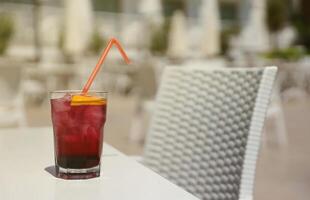 Pink and red Fresh colorful exotic alcoholic cocktail with lemon and ice on restaurant table. Colorful pink Soft drink with ice photo