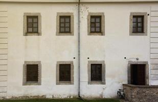 Glass windows on white antique wall of old medieval castle in european suburb photo