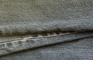 Detailed abstract texture of dark blue denim cloth. Background image of old used denim trousers fabric photo