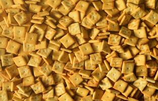 Background texture of small edible squares baked from dough and sprinkled with salt. A lot of salt cracker photo