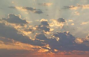 Beautiful sunrise with warm orange sunlight and beams through blue sky photo