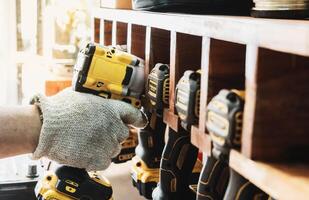 Mechanic reaching for electric screwdriver or electric drill or impact tool on Cordless Tool Shelf Holds to repair motorcycle in garage. maintenance and repair concept . selective focus photo