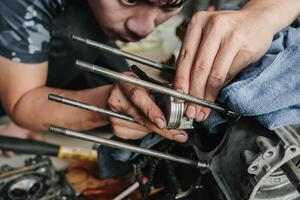 mecánico es instalando un motocicleta pistón en garaje.desmontaje y mantenimiento de motocicleta motor foto