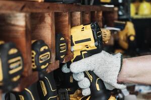 Mechanic reaching for electric screwdriver or electric drill or impact tool on Cordless Tool Shelf Holds to repair motorcycle in garage. maintenance and repair concept . selective focus photo