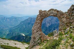 View of circular rock formation in the mountains. Natural monument Hajducka vrata in Cvrsnica mountain. Famous hiking place in Bosnia and Herzegovina. photo