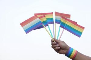 cerca arriba mano sostiene arco iris colores banderas concepto, lgbtq celebracion en orgullo mes, junio. símbolo de lgbt comunidad alrededor el soporte.mundial humano Derecha de género diversidad. foto