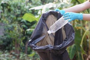 de cerca mano vestir guantes, sostener el plastico botella. concepto, basura gestión, reutilizado, reciclado el plastico botellas mantener limpiar y comunidad Servicio para el mejor ambiente. cero desperdiciar. foto