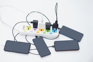 Mobile Phone connected to charging hubs on electric socket. Concept, too many devices plugged in can cause severe damage with appliance as electric shot. Overloaded electrical outlets. Dangerous. photo