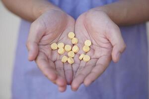 Selective focus on some yellow pain killer medicine pills on hands. Concept, Health care, treatment, remedy illness and self therapy at home. Taking overdose pills. photo