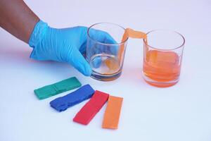 Hand wear blue glove, hold glass of color paper strip to absorb water to another glass.Concept, science lesson activity. Easy experiment for learning. Teaching education materials. Learning design photo