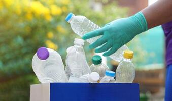 Hand holds used plastic bottle to put in junk bin for recycling. Concept, sorting garbage campaign before throw away for reuse or recycle. Environment conservation. Eco friendly activity. photo