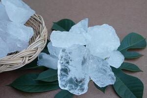Crystal clear alum stones or Potassium alum, decorated with leaves. Useful for beauty and spa treatment. Use to treat body odor under the armpits as deodorant and make water clear. . photo