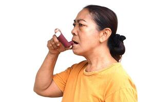 Female senior patient uses brown asthma inhaler for relief asthma. Concept, Health care at home. Pharmaceutical products for treatment symptoms of asthma or COPD. Use under prescription of doctor. photo