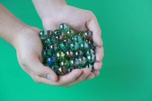 Close up hands holds marbles balls, small spherical object often made from glass, clay, steel, plastic, or agate. Concept. object use as toy for playing games or use for DIY craft decoration. photo