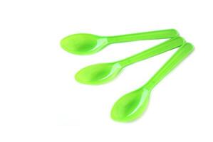 Green plastic disposable spoons isolated on white background. Concept, equipment for eating utensil, can be reuse or recycle to made DIY craft. photo