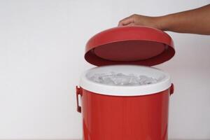 Close up hand open lid of red bucket of ice. Concept, kitchenware container for keep cool of ice, prepare for mix in beverages in party or picnic. Easy and convenient to carry. photo