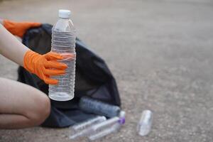 de cerca mano vestir guantes, sostener el plastico botella. concepto, basura gestión, reutilizado, reciclado el plastico botellas mantener limpiar y comunidad Servicio para el mejor ambiente. cero desperdiciar. foto