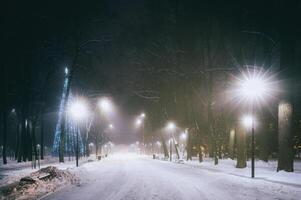 Winter park at night with christmas decorations, glowing lanterns and trees covered with snow. Vintage film aesthetic. photo