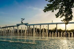 monumento y filas de fuentes iluminado por luz de sol a puesta de sol o amanecer en el independencia cuadrado a Hora de verano, Taskent. foto