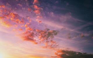 Dramatic cloudy sky illuminated by the rays at sunset or sunrise. Vintage film aesthetic. photo