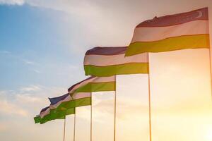 Flags of Uzbekistan waving on a sunset or sunrise dramatic sky background. photo