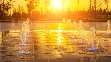 Small fountains on the sidewalk, illuminated by sunlight at sunset or sunrise at summertime. photo