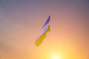 Flag of Uzbekistan waving on a sunset or sunrise dramatic sky background. photo