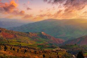 Foggy sunset or dawn in the mountains covered with grass and cloudy dramatic sky. photo