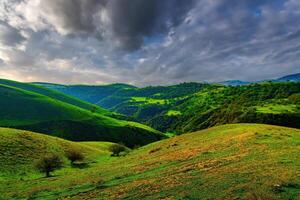 Hills and mountains covered with young green grass and illuminated by the sun on a sunny day. photo