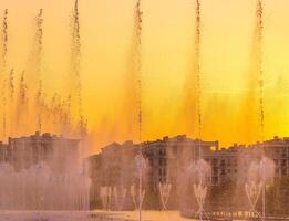 Big fountains on the artificial pond, illuminated by sunlight at sunset in Tashkent city park at summertime. photo